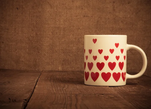 Taza con muchos corazones en la vieja mesa de madera. Tonificado — Foto de Stock