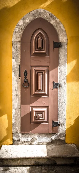Old wooden door with metal hinges and lock on the yellow wall. T — Stock Photo, Image