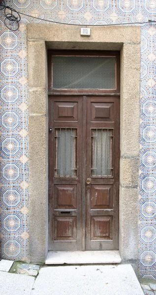 Старая деревянная дверь с окном на стене с керамической плиткой — стоковое фото