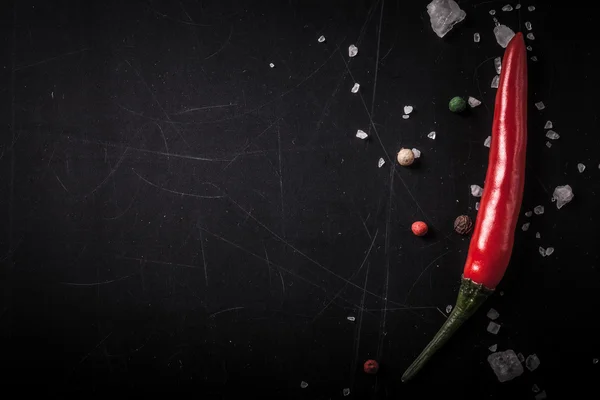 Red hot chilli pepper with sea salt and colored pepper on black — Stock Photo, Image