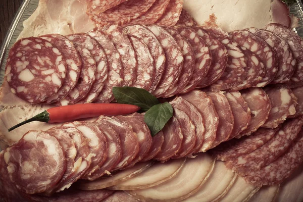 Plate with different kinds of sliced sausage and red hot chilli — Stock Photo, Image
