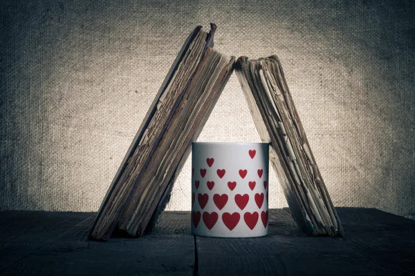 Libros antiguos y jarra con muchos corazones en la vieja ta de madera — Foto de Stock