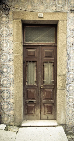 Stare drewniane drzwi z okna na ścianę z płytek ceramicznych. Stonowanych — Zdjęcie stockowe