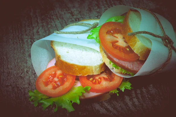 Сэндвич с бечевкой на деревянной доске. Toned — стоковое фото