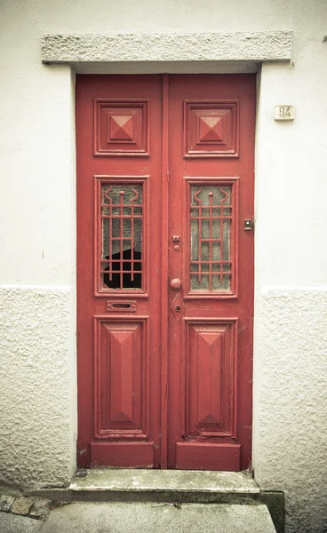 Alte rote Holztür mit Fenster und Gitter. gemildert — Stockfoto