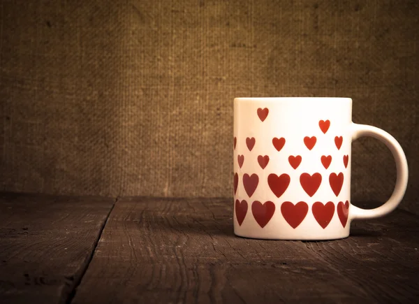 Taza con muchos corazones en la vieja mesa de madera. Tonificado — Foto de Stock