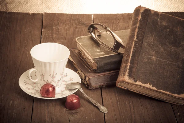 Tasse Kaffee, Shokolad, Gläser und Stapel alter Bücher auf dem o — Stockfoto