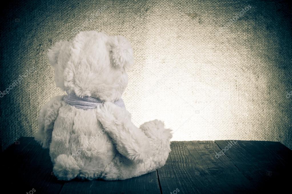 Teddy bear is sitting on the old wooden table. Toned