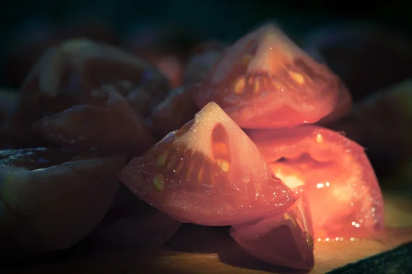 Pedaços de tomates em uma tábua de madeira. Baixa luz e raso dept — Fotografia de Stock