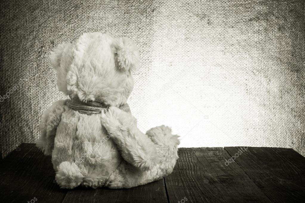 Teddy bear is sitting on the old wooden table. Toned