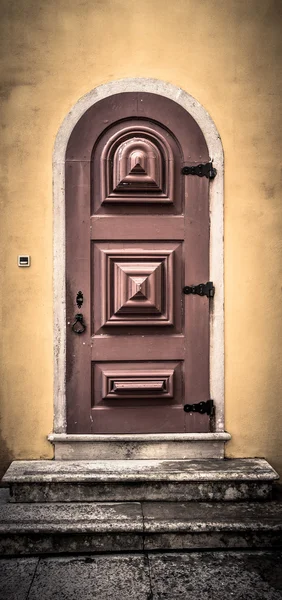 Vieille porte en bois avec charnières en métal et serrure sur le mur jaune. T — Photo