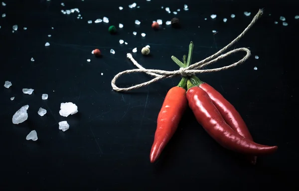 Three hot red chili pepper related by twine with sea salt and co — Stock Photo, Image