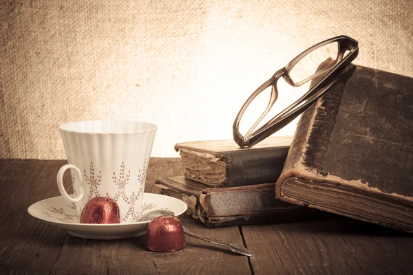 Cup of coffee, shokolad, glasses and stack of old books on the o — Stock Photo, Image