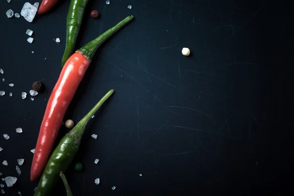 Červené a zelené feferonky s mořskou solí a barevným pepřem — Stock fotografie