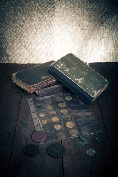 Vintage books and coins on old wooden table. Toned — Stock Photo, Image