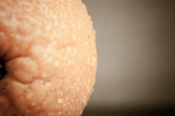 Naranja con gotas de agua en el primer plano de la piel sobre un fondo claro —  Fotos de Stock