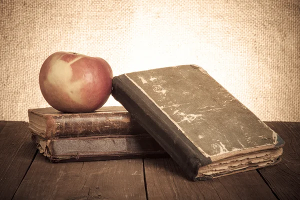 Bodegón con manzana y un montón de libros viejos en la vieja pestaña de madera — Foto de Stock