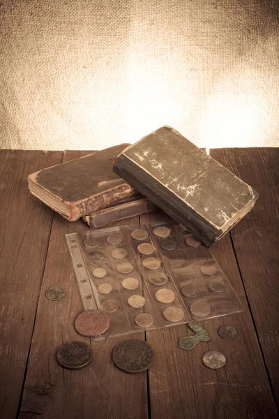Bücher und Münzen auf einem alten Holztisch. gemildert — Stockfoto