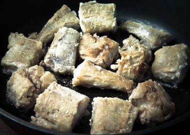 Bazı parçaları bir tavada kızarmış balık fileto. Tonda