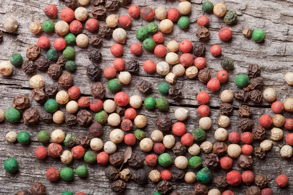 Bunte Pfefferkörner auf einem alten Holztisch — Stockfoto