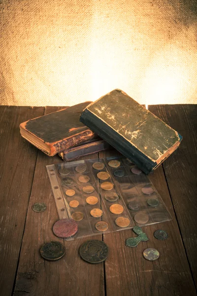 Vintage books and coins on old wooden table. Toned — Stock Photo, Image
