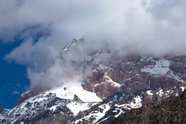Des nuages se trouvent sur les sommets enneigés des rochers. Paysage — Photo