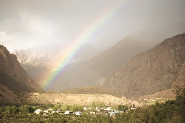 Regenbogen über dem Dorf in den Bergen. Landschaft. gemildert — Stockfoto