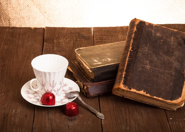 Tasse Kaffee, Shokolad und Stapel alter Bücher auf dem alten Holz — Stockfoto