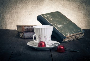 Fincan kahve, shokolad ve eski ahşap eski kitap yığını