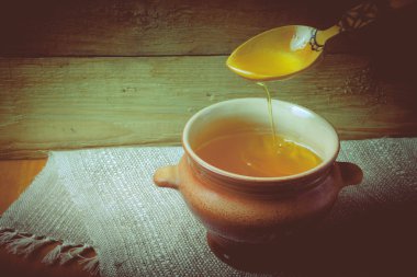 Ghee ve kaşık keten peçete ile toprak kap. Rustik natürmort.