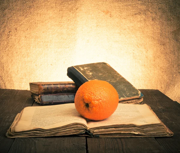 पुरानी लकड़ी की मेज पर नारंगी और पुरानी किताबों के साथ अभी भी जीवन। टोंड — स्टॉक फ़ोटो, इमेज