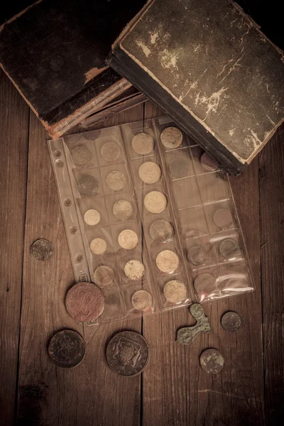 Libros y monedas de época sobre una vieja mesa de madera. Tonificado —  Fotos de Stock