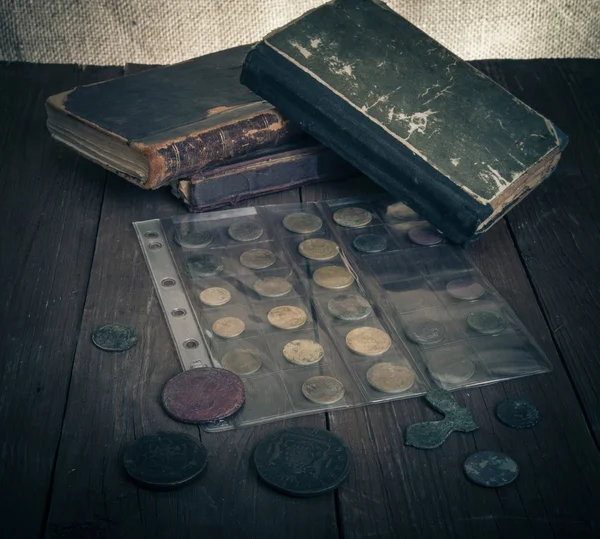 Vintage books and coins on old wooden table. Toned — Stock Photo, Image