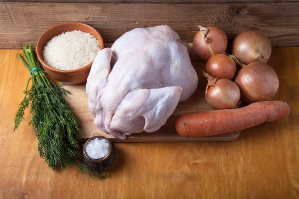 Ganze rohe Hühner, Zwiebeln, Karotten, Dill, Reis, Salz auf Holzbac — Stockfoto