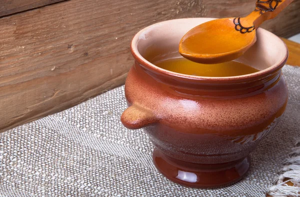 Clay pot with ghee and spoon on linen napkin. Rustic still life. — Stock Photo, Image