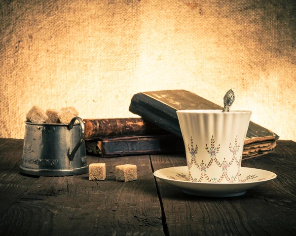 Kopje koffie, een suikerpot en een stapel oude boeken op het oude hout — Stockfoto