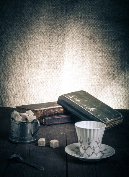 Kopje koffie, een suikerpot en een stapel oude boeken op het oude hout — Stockfoto