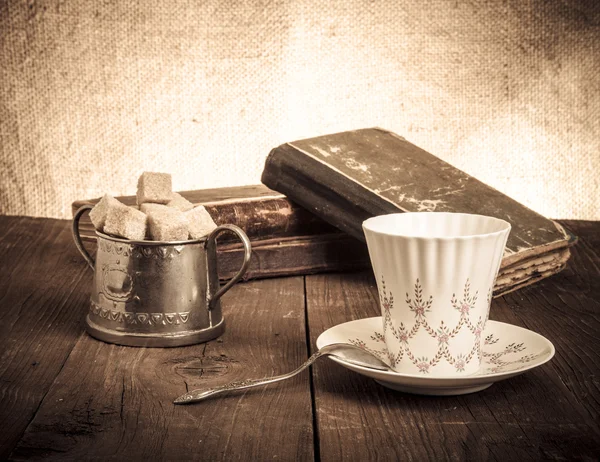 Kopje koffie, een suikerpot en een stapel oude boeken op het oude hout — Stockfoto