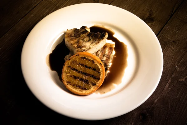 Carne alla griglia con arancia su piatto di ceramica bianca su vecchia ta di legno — Foto Stock