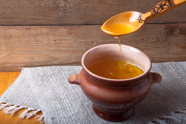 Выложить горшок с гхи и ложкой на льняную салфетку. Сельский натюрморт
.