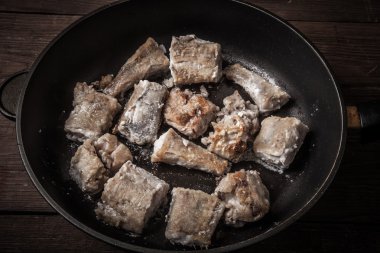 Bazı parçaları bir tavada kızarmış balık fileto. Tonda