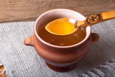 Ghee ve kaşık keten peçete ile toprak kap. Rustik natürmort.