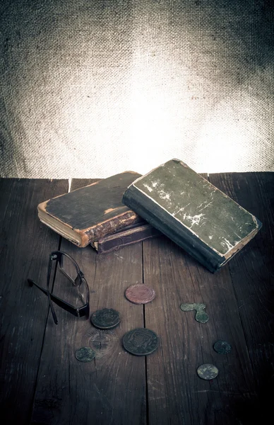 Libros y monedas de época y espectáculos sobre una vieja mesa de madera. Tono — Foto de Stock