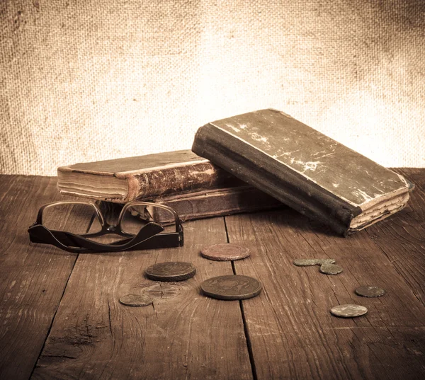 Εκλεκτής ποιότητας βιβλία και κέρματα και θεάματα στο παλιό ξύλινο τραπέζι. Τόνος — Φωτογραφία Αρχείου