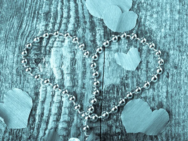 Many Valentine hearts and shiny beads on the old wooden table. T — Stock Photo, Image