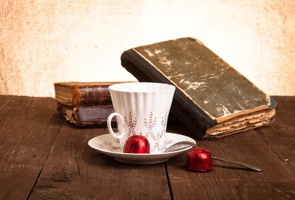 Šálek kávy, shokolad a stoh starých knih na staré dřevěné — Stock fotografie