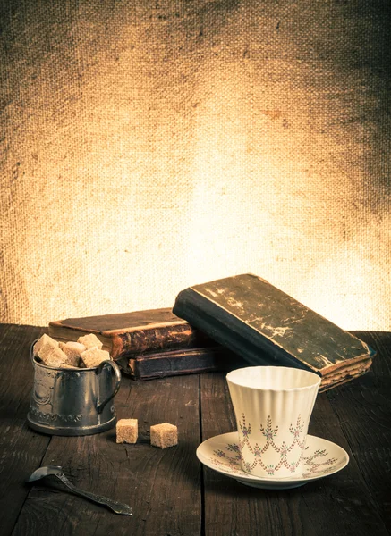 Kopje koffie, een suikerpot en een stapel oude boeken op het oude hout — Stockfoto