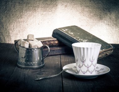 Fincan kahve, şekerlik ve eski kitap eski odun yığını