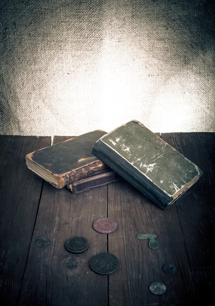 Livres anciens, pièces de monnaie et lunettes sur une vieille table en bois. Ton : — Photo