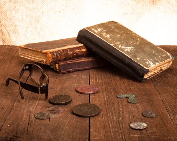 Libros y monedas de época y espectáculos sobre una vieja mesa de madera. Tono —  Fotos de Stock